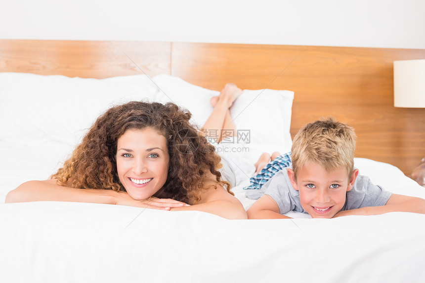 母亲和儿子在床上微笑 看着摄像机躺在床上图片