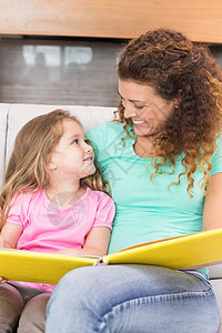 快乐的母亲与她女儿坐在一起看故事书的幸福母亲背景图片