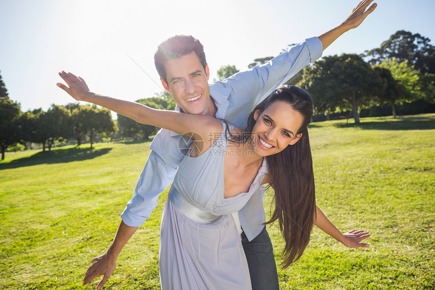 快乐的一对夫妇 在公园伸出双臂成人闲暇天空情人男人幸福头发伙伴女朋友棕色图片