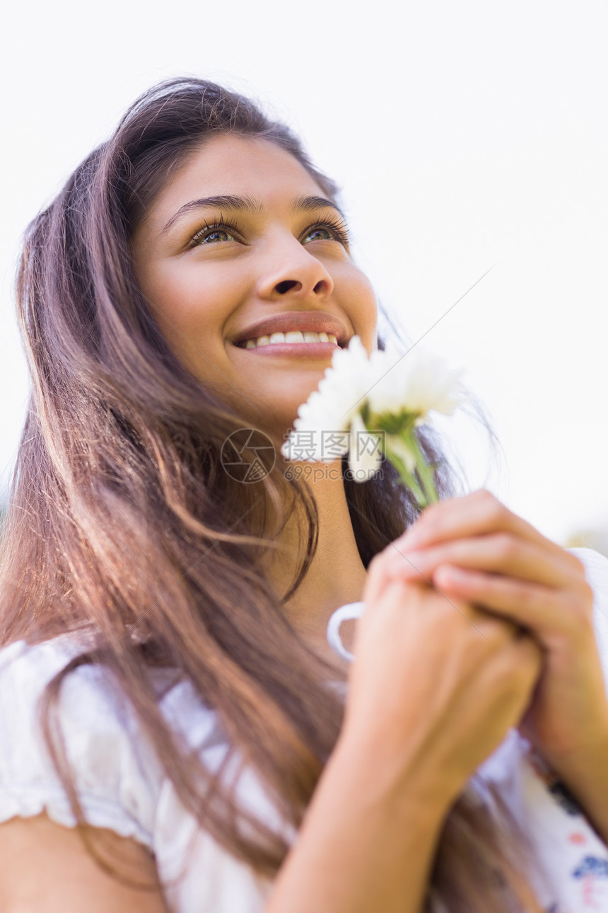 一个带着鲜花微笑的年轻女子的近身图片