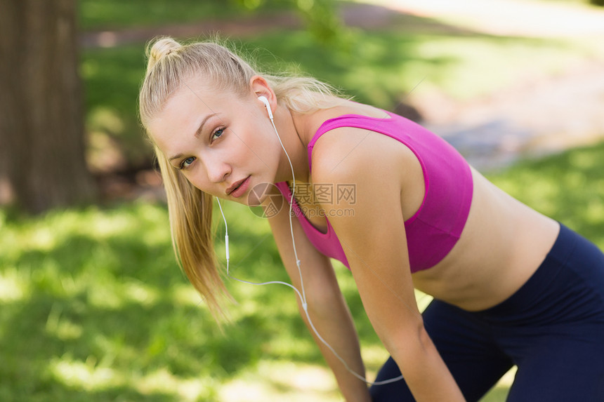 在公园穿运动胸罩的 疲劳美丽的女人慢跑金发调子浅色赛跑者慢跑者护理头发闲暇耳机图片