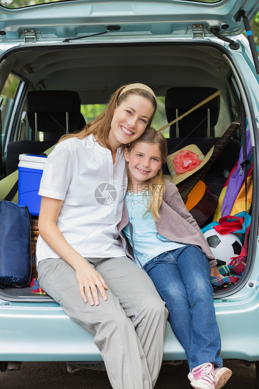 坐在汽车后备箱里的母亲和女儿微笑女士家庭运输树干车辆闲暇旅行喜悦团结农村图片