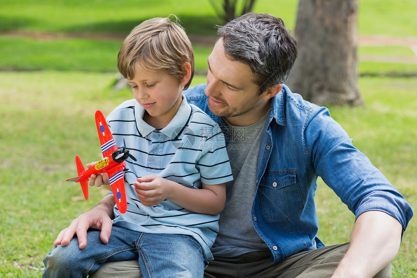 男孩玩具飞机坐在父亲的腿上图片