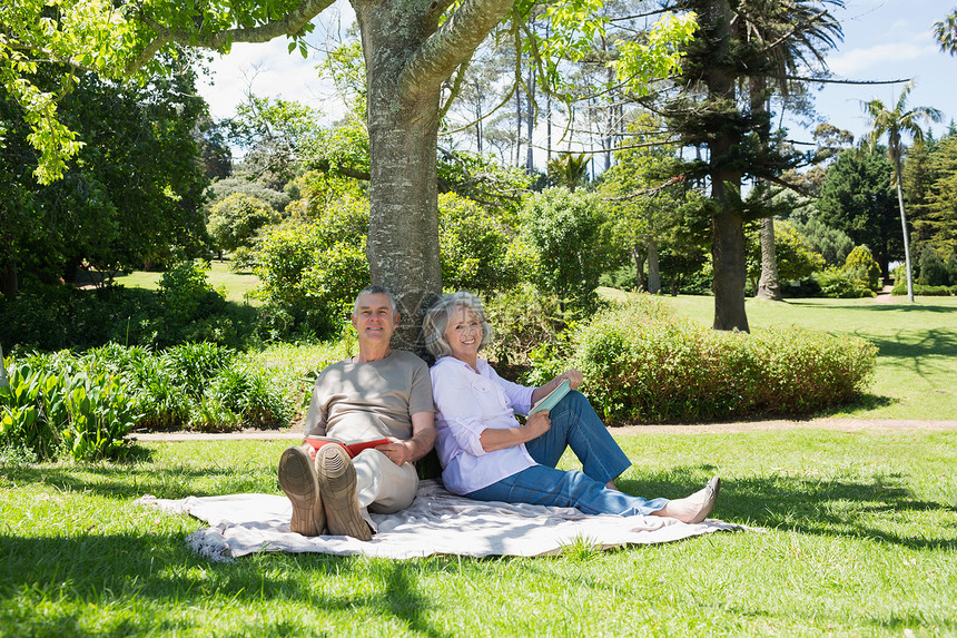 坐在公园树边的笑笑成年夫妇页数树干头发牛仔布阅读夫妻男性小说倾斜知识分子图片