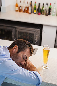 醉酒商务人士睡在啤酒杯边高清图片