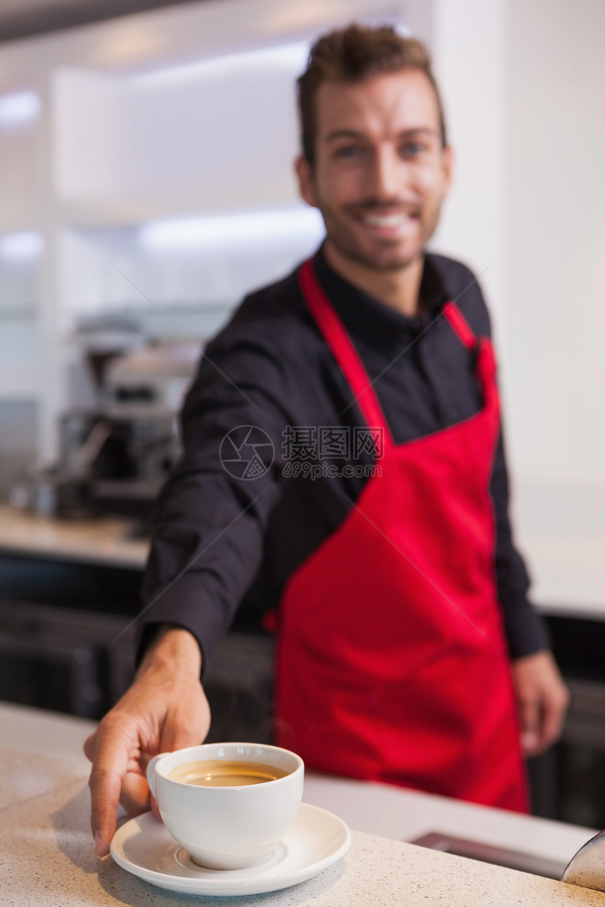快乐的年轻咖啡师 把一杯咖啡倒在柜台上图片