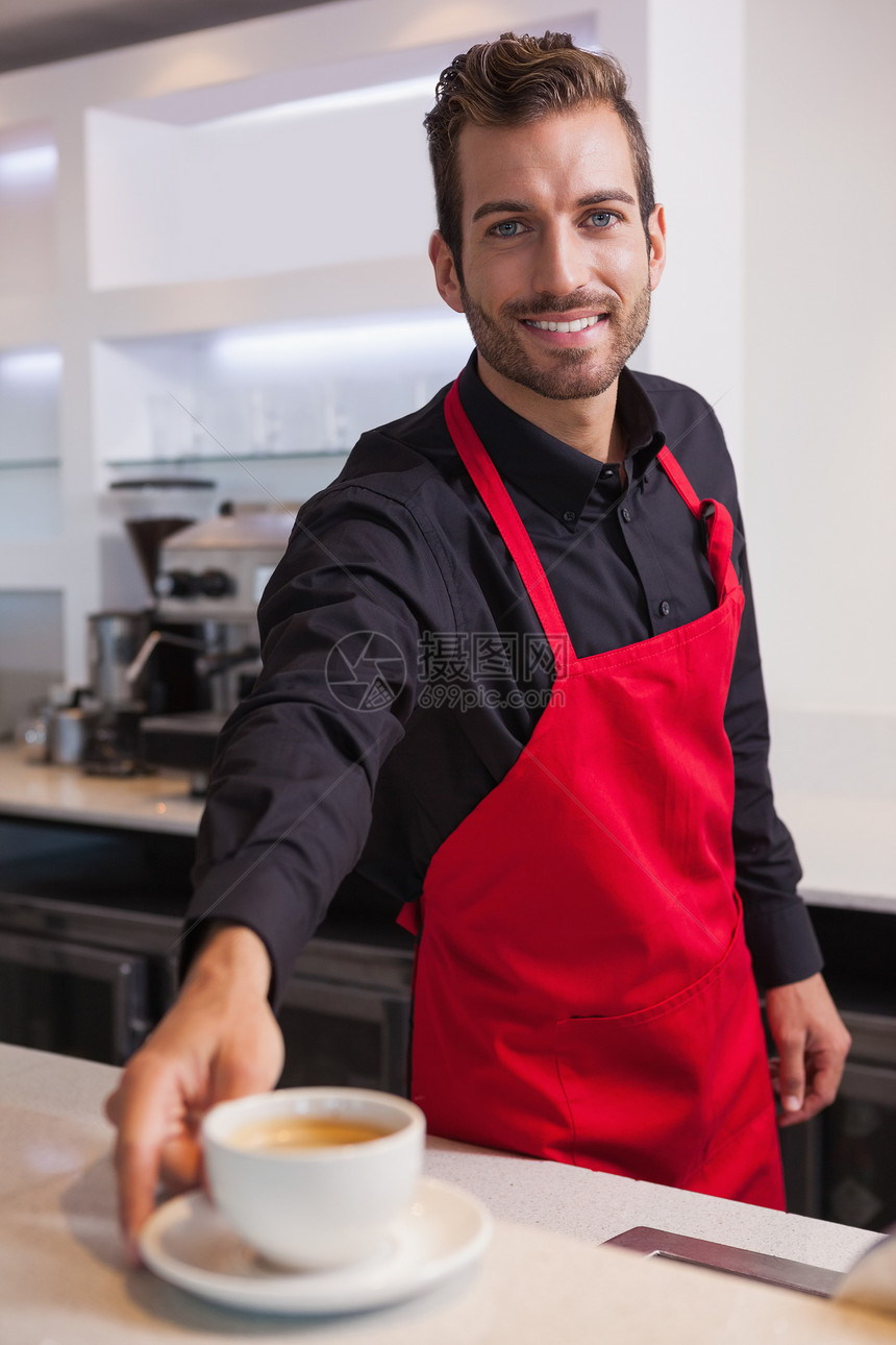 微笑的年轻咖啡师 在柜台上倒咖啡杯图片