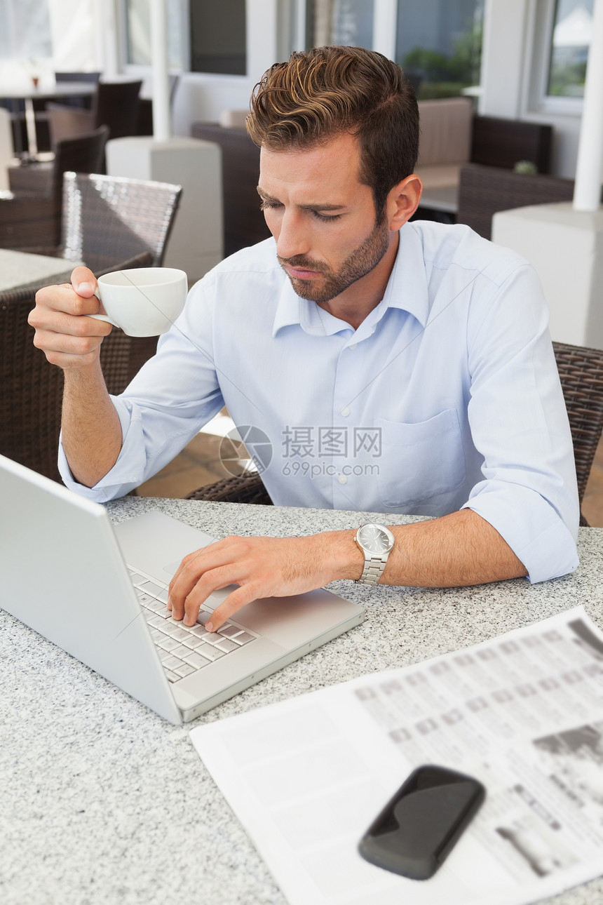 年轻商务人士用笔记本电脑握着咖啡杯图片
