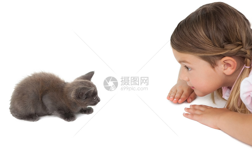 可爱的小女孩看着灰小猫躺在地上图片