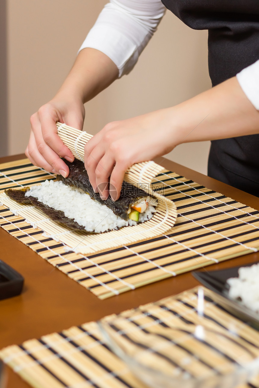 女厨师的手卷起日本寿司黄瓜海鲜竹子饮食鱼片餐厅海苔美食女士食物图片