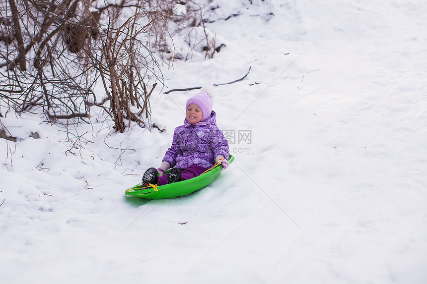 可爱的小女孩在雪地森林滑雪图片