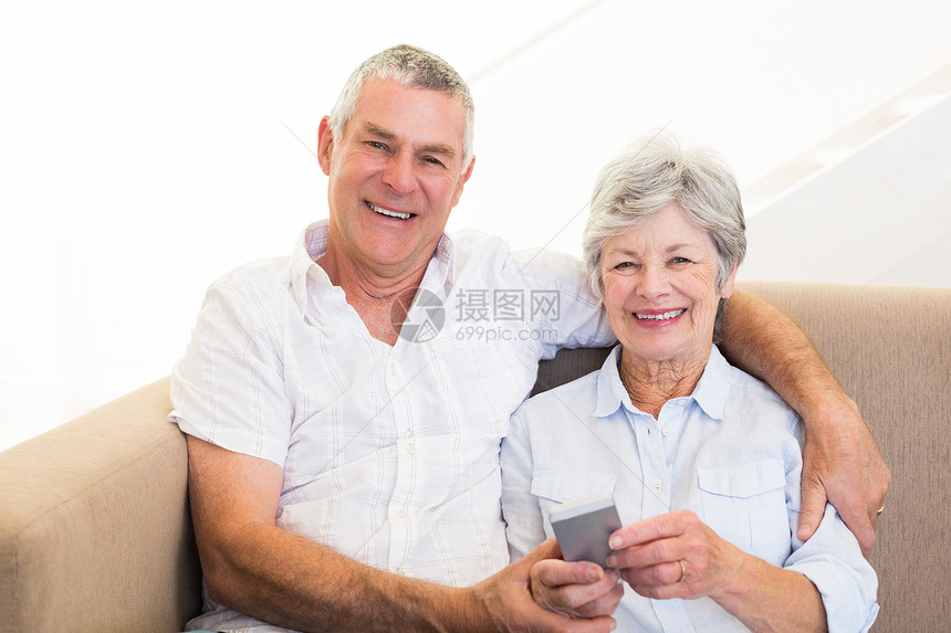 使用移动电话的微笑夫妇老年休闲女性夫妻男人手机拨号沙发技术白发图片
