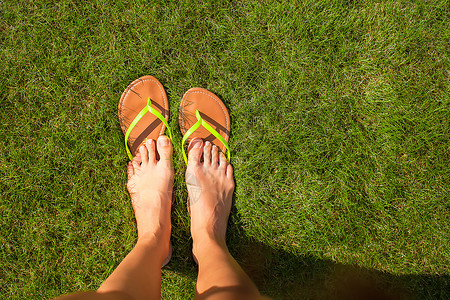 手掌拖脚在绿草上用拖鞋紧紧女人的腿配饰衣服字拖阳光旅行装饰品黄色绿色娱乐热带背景