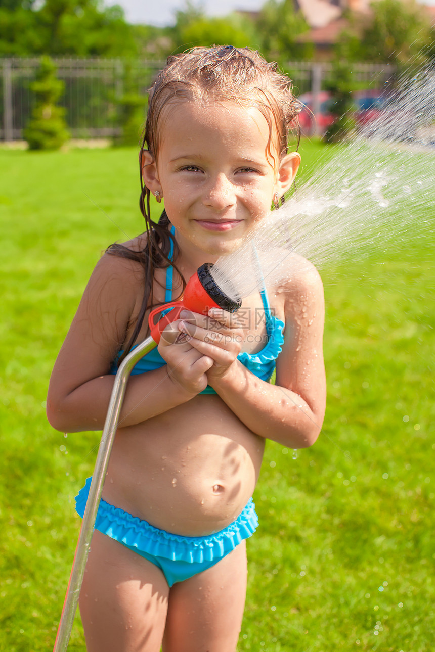 快乐可爱可爱的小女孩微笑 从水管里倒水喷泉花园液体喜悦园艺女孩幸福女儿孩子流动图片