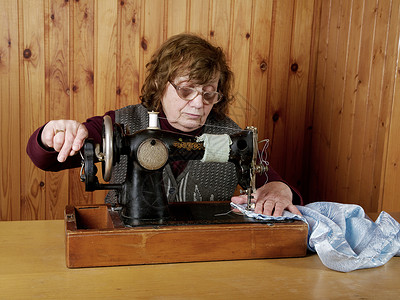 那个老太婆在缝纫机上缝衣服背景图片