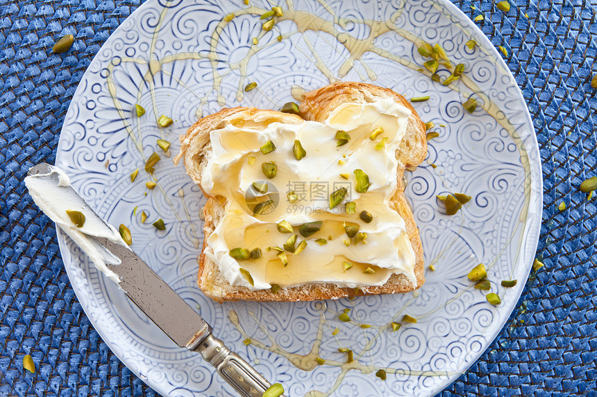 配奶油奶酪和蜂蜜开心果蓝色食物盘子包子坚果早餐小吃面包图片