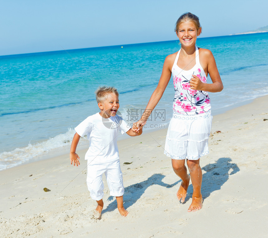 海滩上可爱的男孩女孩太阳海景孩子假期异国情调支撑海岸线活动女性图片