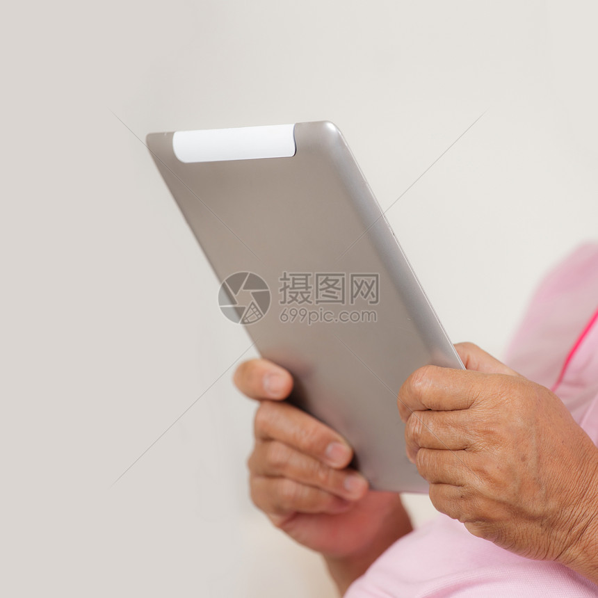高级男子使用数字平板电脑男人长椅技术灰色房子人士男性软垫老年人白色图片
