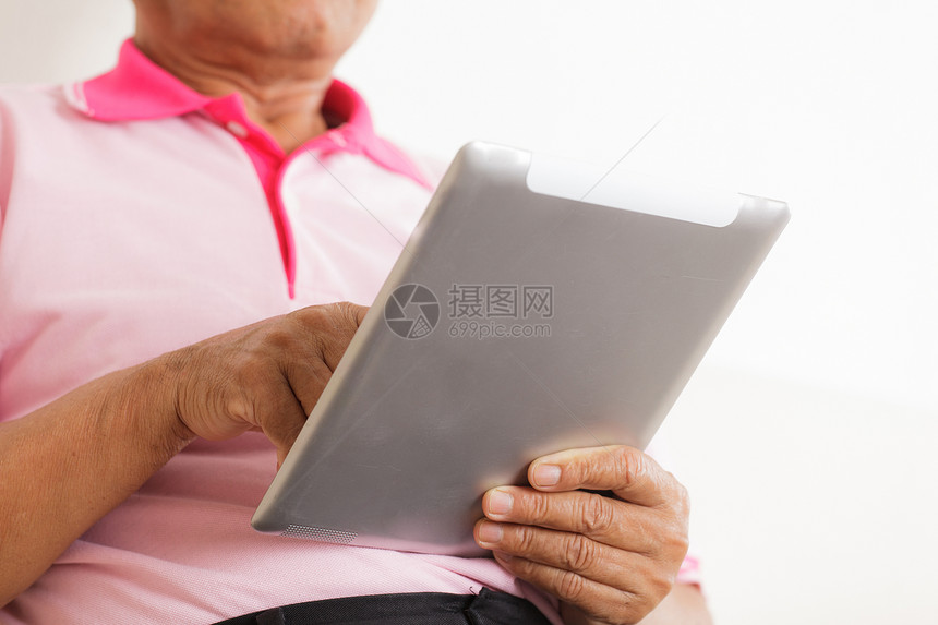 高级男子使用数字平板电脑头发技术互联网白色退休房子成人老年人沙发男人图片