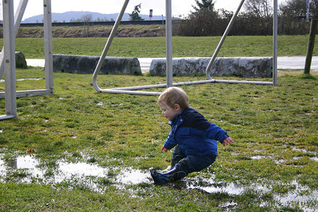 滑过足球场婴儿水坑白色蓝色孩子靴子足球背景图片