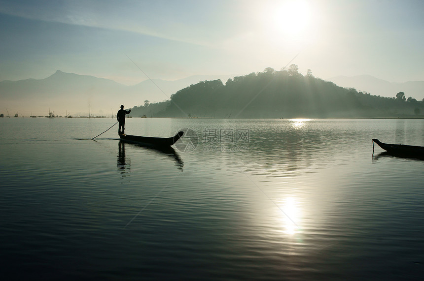 湖上日出 渔民在船上划船图片