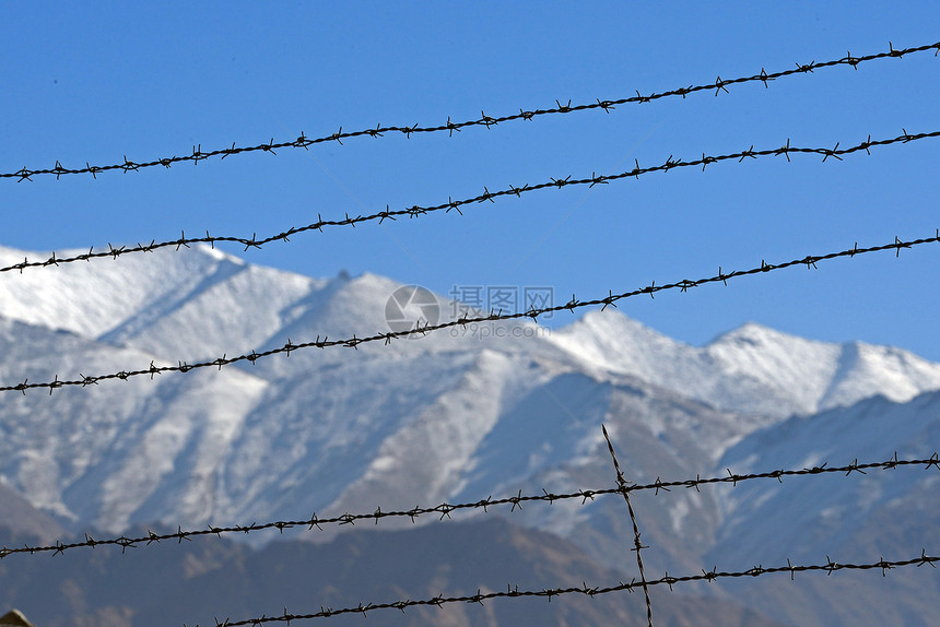 冬季被刺穿的铁丝网围栏 有雪山背景木头白色冻结柱子邮政山脉天空蓝色栅栏薄片图片