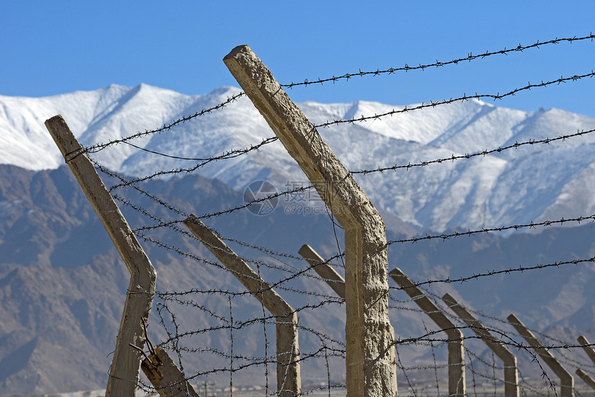 冬季被刺穿的铁丝网围栏 有雪山背景冻结蓝色柱子邮政薄片天空山脉栅栏白色木头图片