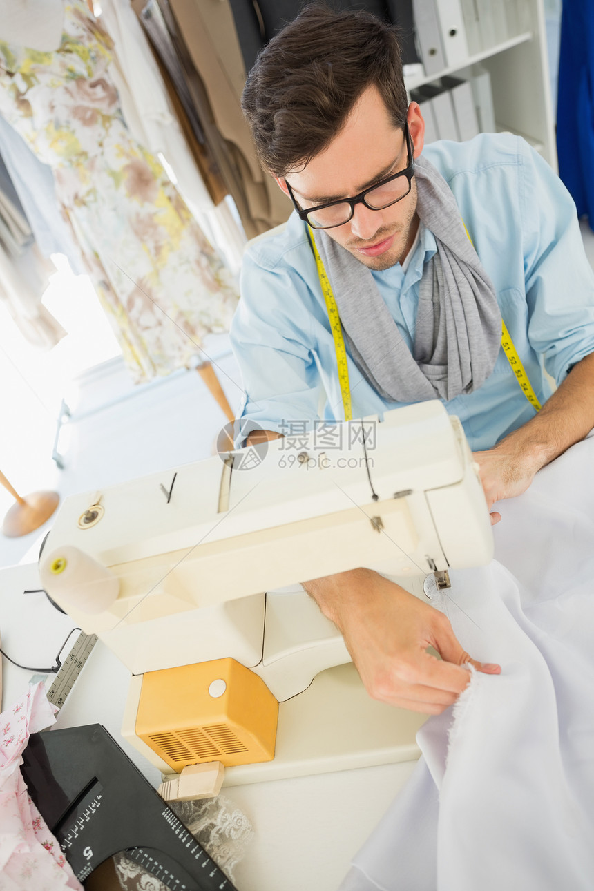 车间中的男性缝制缝纫眼镜时装工作室自雇材料织物定制卷尺专注作坊图片