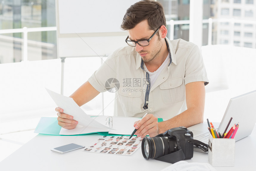 集中男性艺术家与照片坐在桌上的桌子上摄影男人女性眼镜设计师编辑工作职场混血便服图片