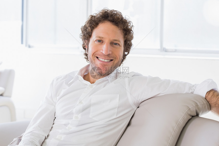 家里一个穿衣良好的年轻人的肖像衬衫男人男性家庭生活长椅棕色房子头发卷发沙发图片