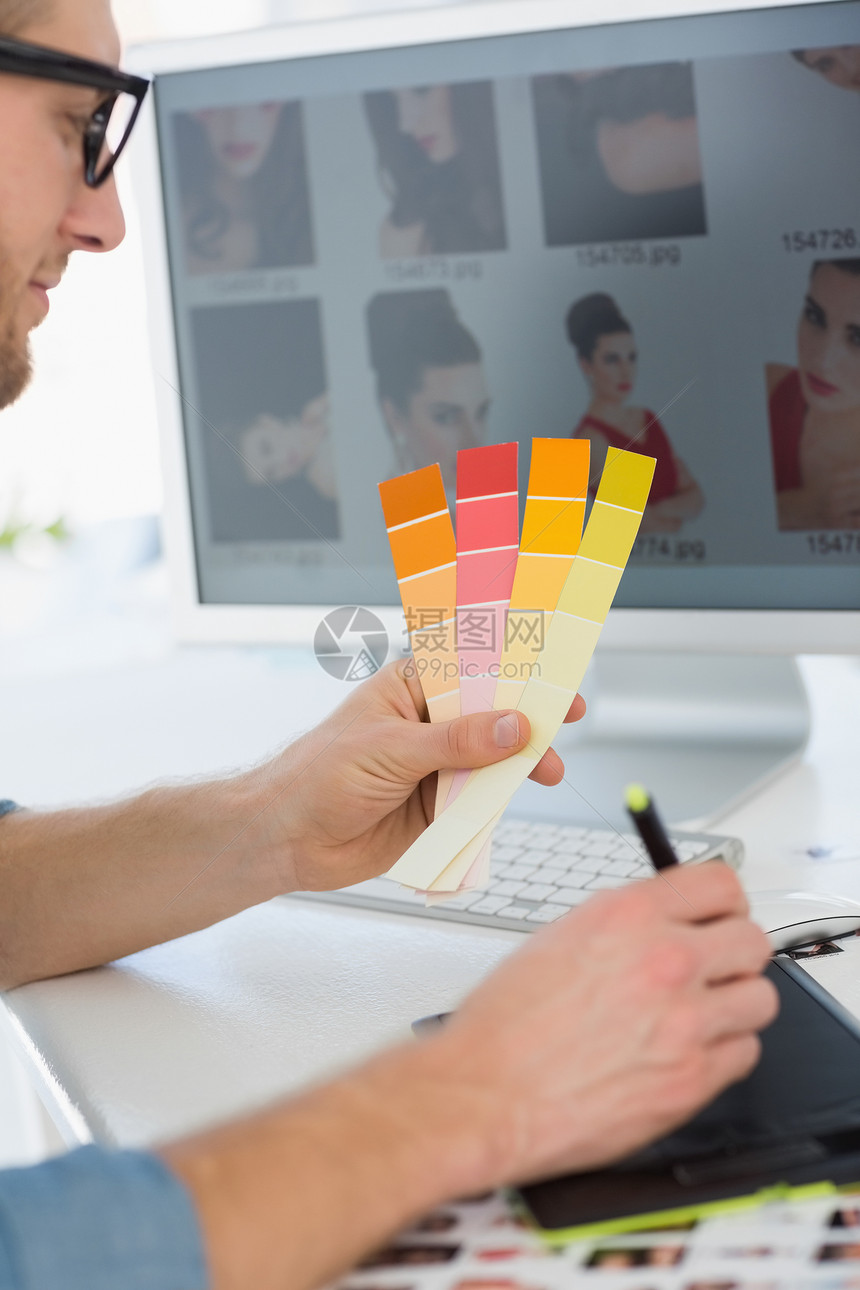 英俊设计师 在办公桌上与数字仪一起工作 持有彩色图表图片
