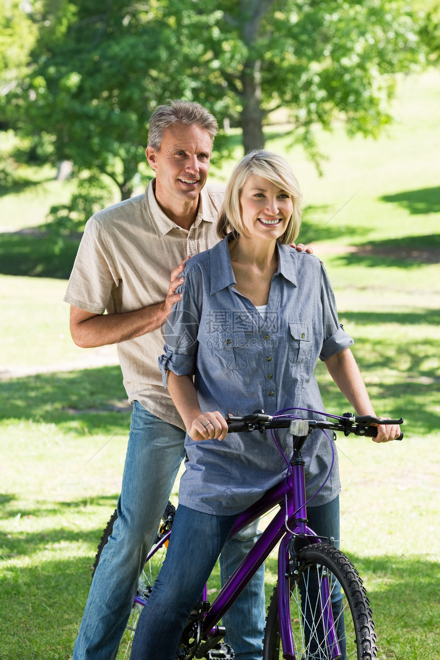 夫妇在公园骑自行车成人男人享受绿地男性微笑娱乐骑术女性亲热图片