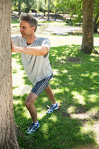 人靠在树上农村公园空闲运动男性阳光热身闲暇运动服成人背景图片