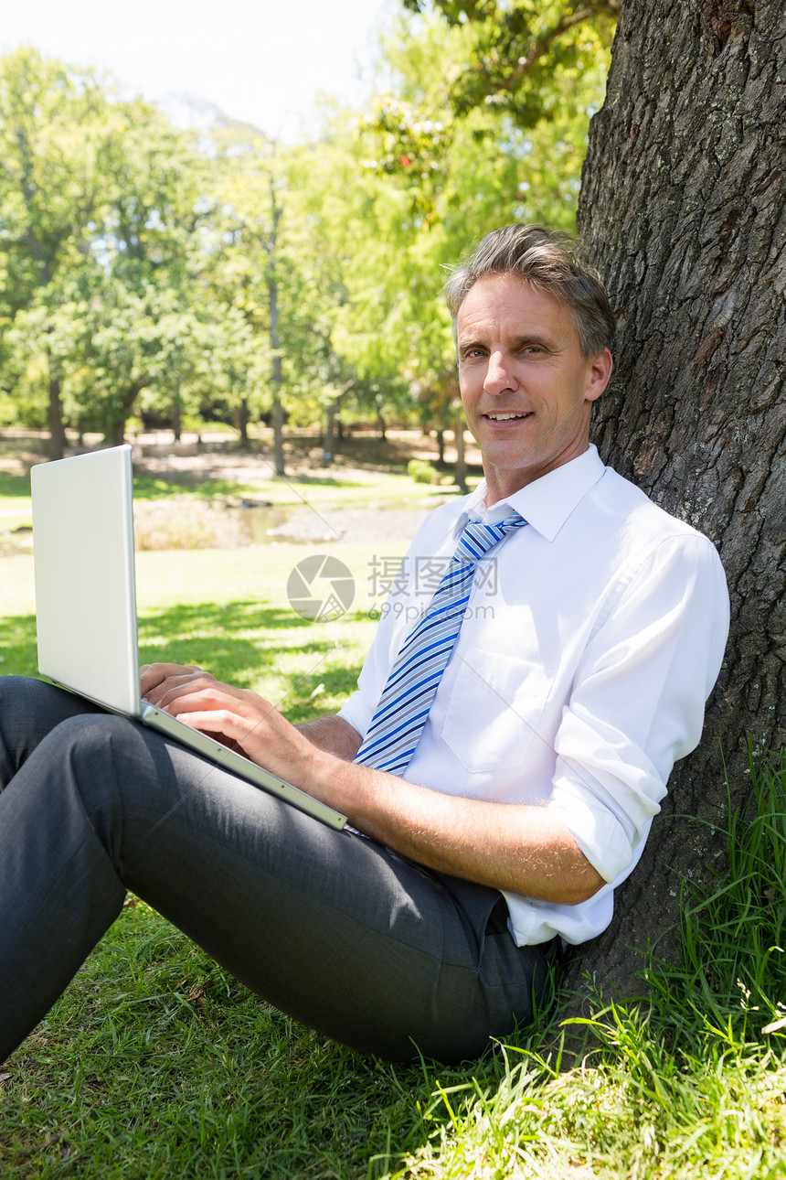 自信的商务人士 在公园用笔记本电脑闲暇男性休息树干生意人人士技术衬衫沟通商务图片