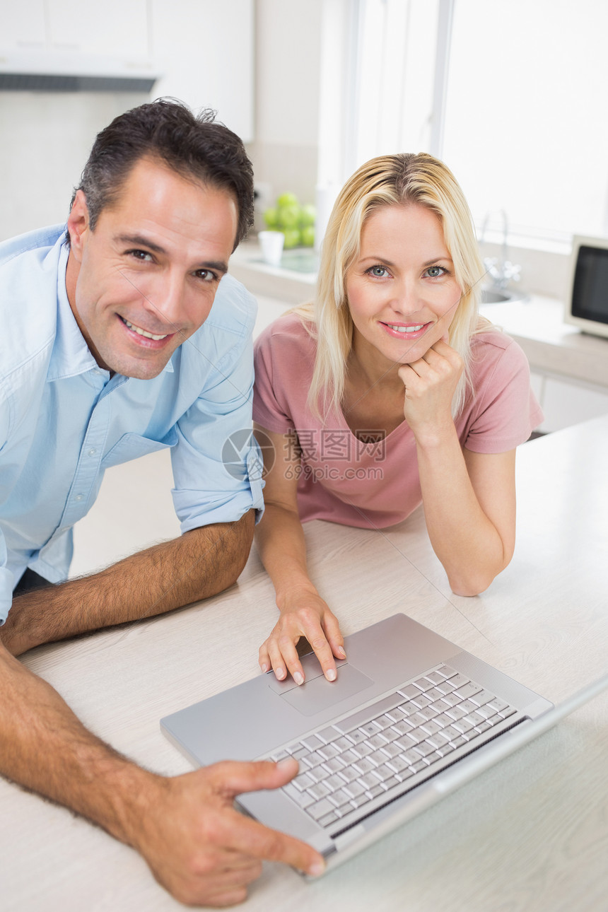 在厨房使用笔记本电脑的一对微笑夫妇女性技术女士房子男人夫妻男性闲暇家庭生活柜台图片