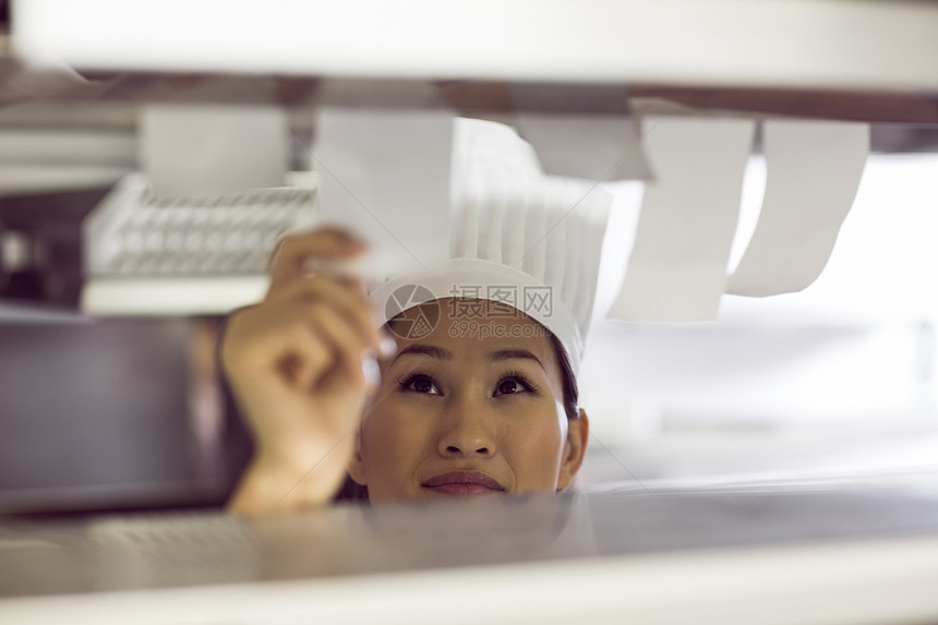 女厨师在厨房通过烹饪核对表清单职业商业帽子命令柜台专注女士餐厅工作图片