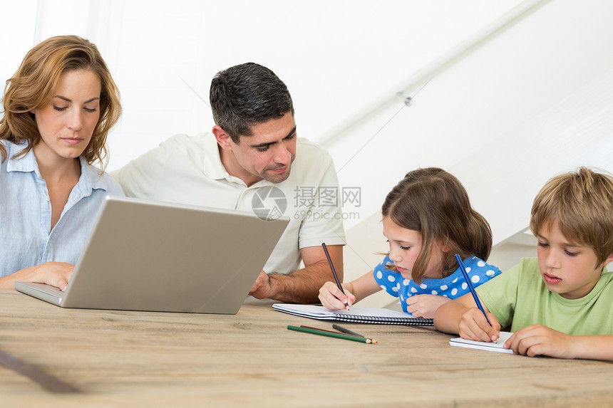 母亲使用笔记本电脑 而父亲帮助子女涂色图片