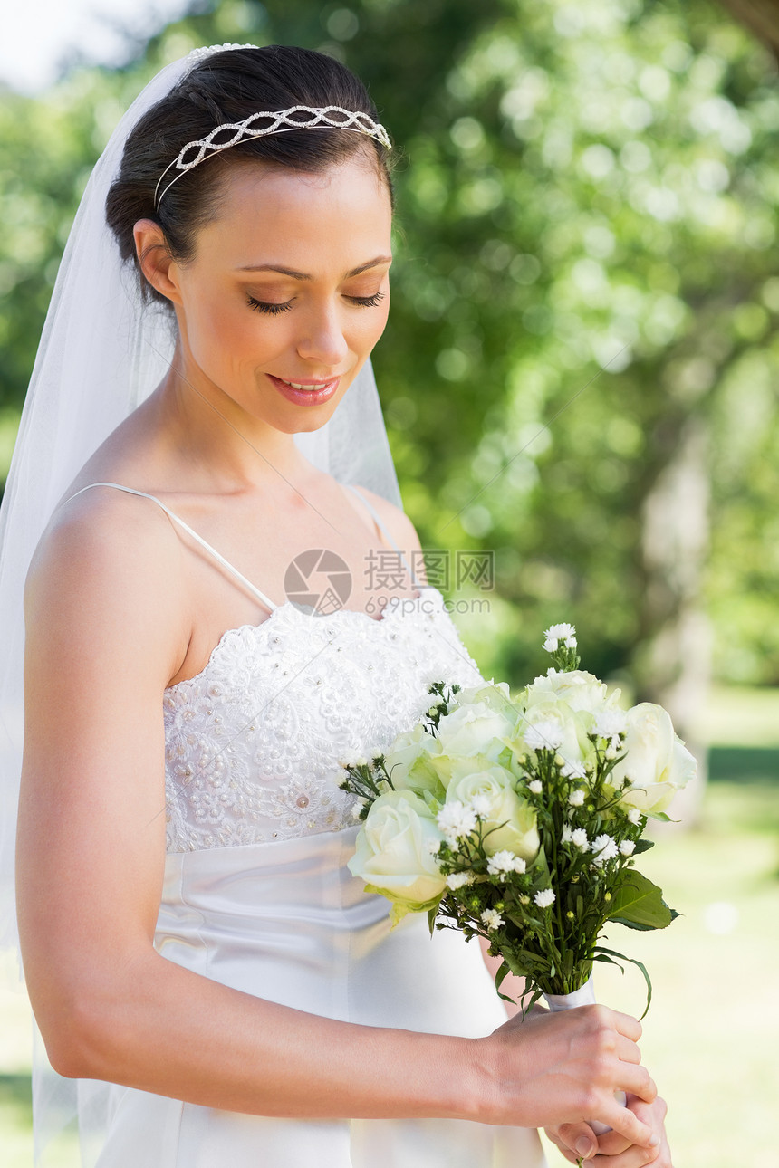 在花园里拿着花束的害羞新娘微笑女性女士开端事件生活婚礼婚纱面纱图片