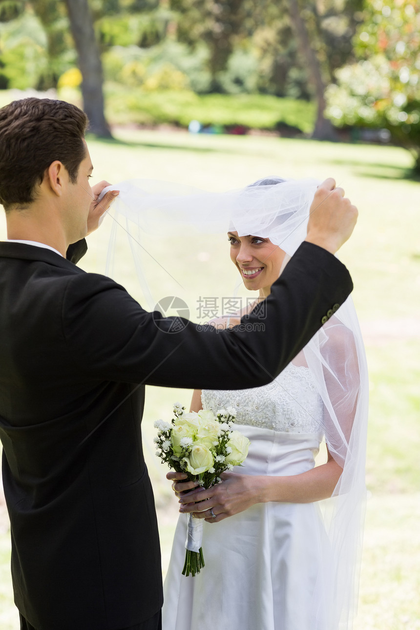 爱新郎的新娘揭开面纱套装丈夫新婚女士婚礼妻子公园微笑起重婚姻图片