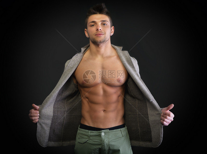 有吸引力的年轻男子 穿着肌肉胸肌的露口夹克工作室外套成人运动白色腹肌相机男性微笑黑色图片