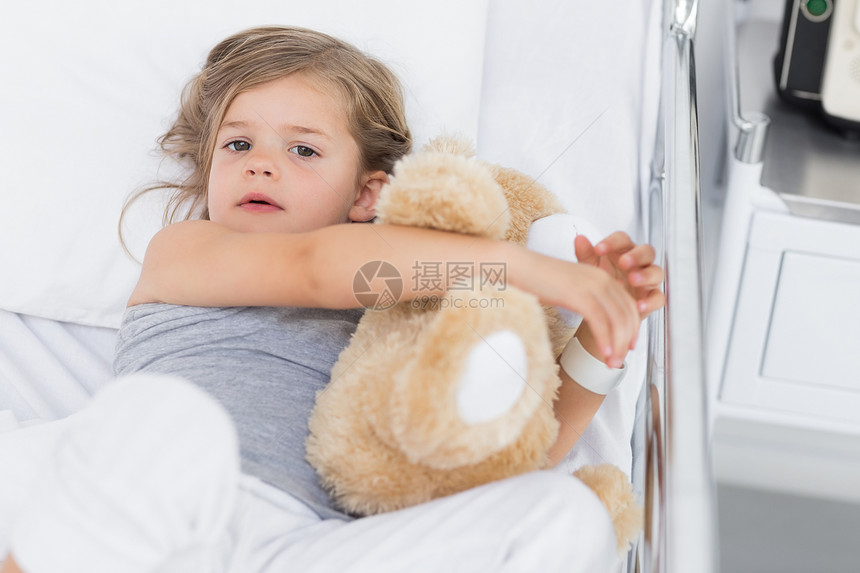 在医院床上拥抱泰迪熊的可爱女孩床单医疗疾病女性玩具说谎病人玩具熊恢复诊所图片