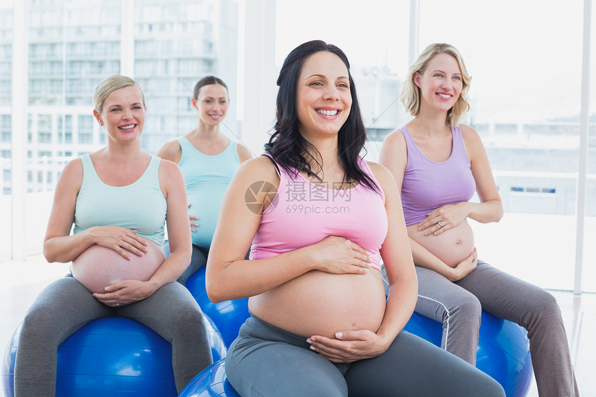 快乐的孕妇们坐在运动球上图片