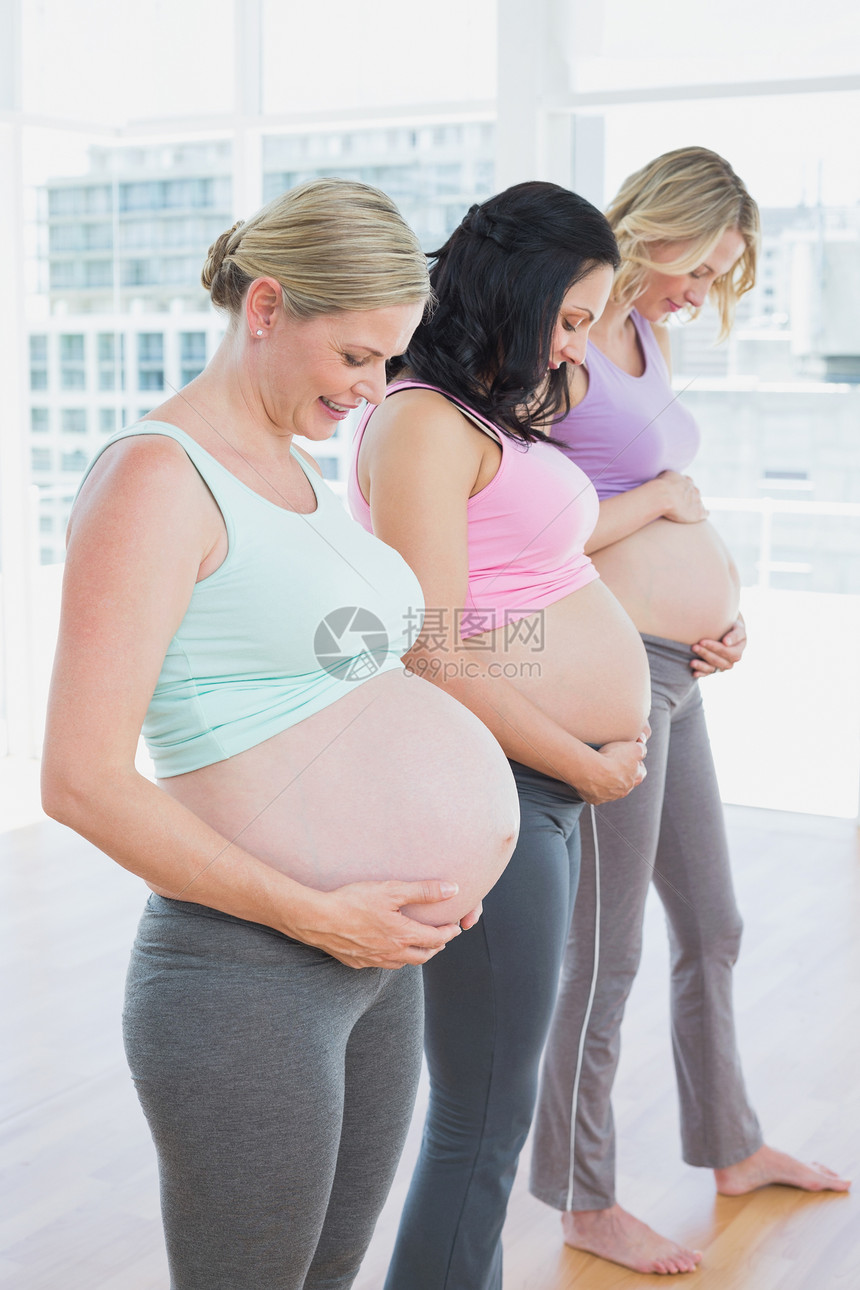 站在一排边上欢笑着微笑着的孕妇们图片