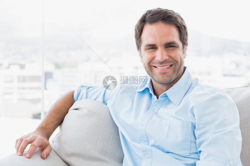 坐在沙发上微笑的英俊男人看着摄像机图片