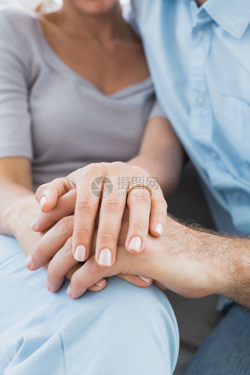 一对夫妇在沙发上用女人的手指 显示结婚戒指图片