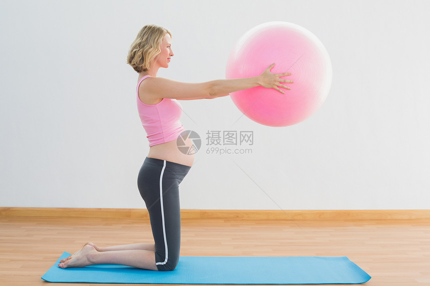 愉快的金发女孕妇举球锻炼图片