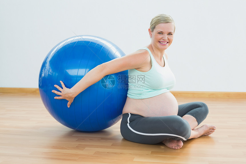 快乐的孕妇坐在运动舞会旁 坐着快乐的孕妇图片
