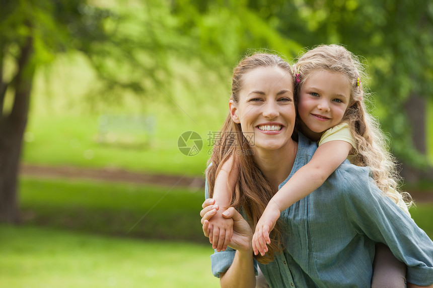 妇女在公园携带女孩的肖像金发女郎母亲女性童年家庭草地乐趣头发浅色享受图片