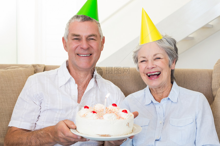 坐在沙发上庆祝生日的年长夫妇客厅男人快乐盘子闲暇长椅公寓感情房子头发图片