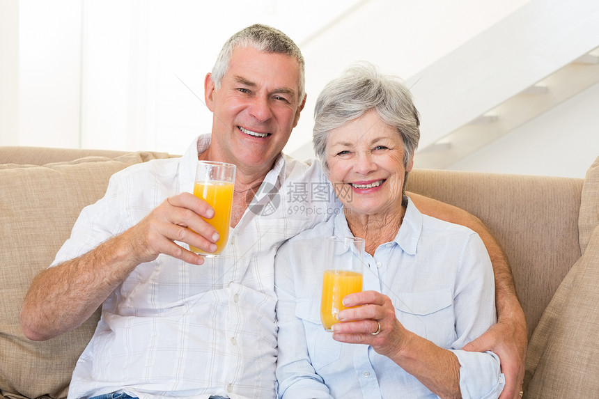 坐在沙发上喝橙汁的老夫妇微笑男性拥抱岁月客厅退休感情老年头发男人图片